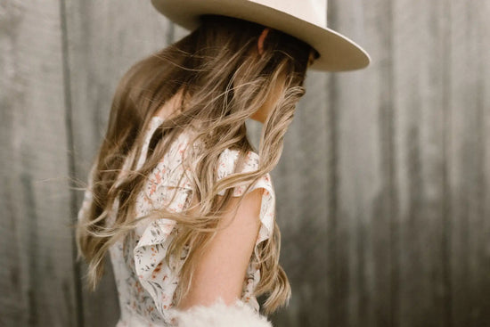 Woman with wavy hair wearing a hat.
